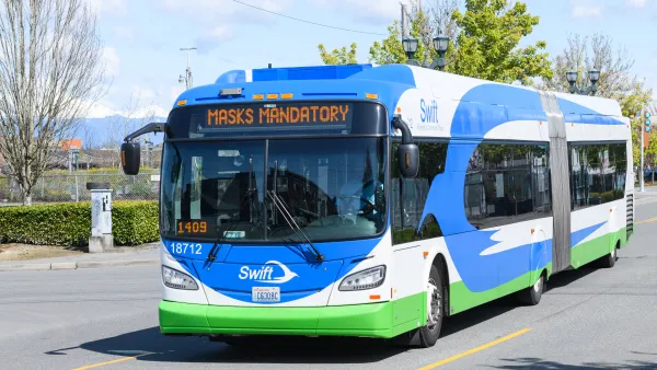 Blue and white bus driving toward the camera with a white logo of a bird that says Swift on the front..