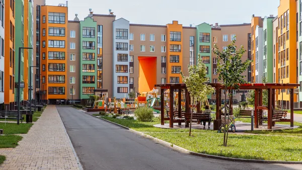 Colorful seven-story apartment buildings around a grasy courtyard with wooden gazebos.