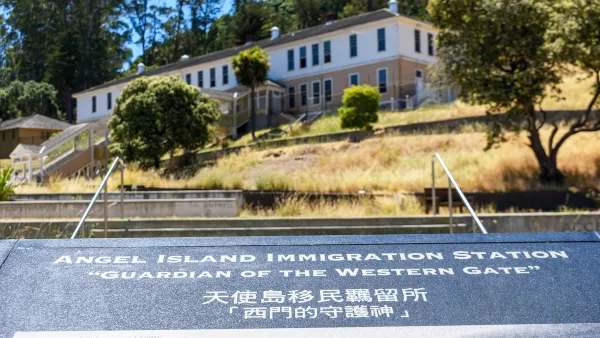 Close-up of plaque at Angel Island Immigration Station, California with historic building in background.