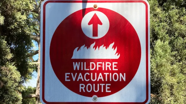 Red and white "Wildfire Evacuation Route" sign on signpost.