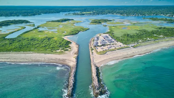 Aerial view of canal cut into beach in Charlestow, Rhode Island with boats parked in sand.