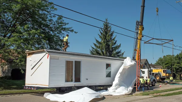 White modular home being installed on a lot.