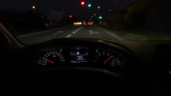 Close-up of car dashboard with speedometer at 35 on roadway at night.