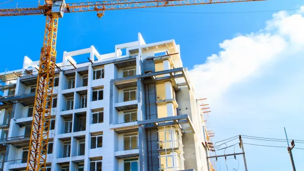 Multistory apartment building under construction with yellow crane.