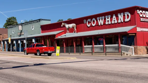 Single-story western-style buildings in Woodland Park, Colorado. Red building on corner labeled "COWHAND" in white text.