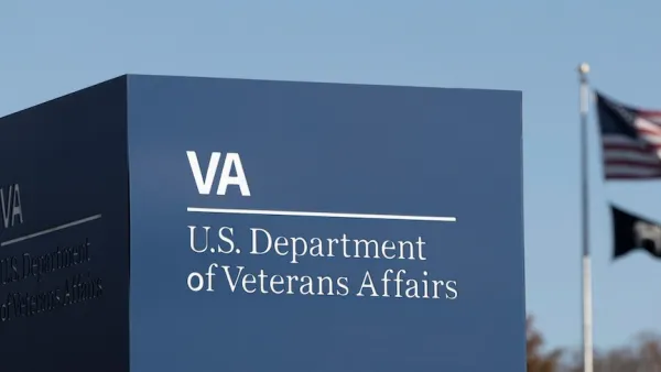 Close-up of Department of Veterans Affairs sign in Washington, D.C. with American and MIA flags on flagpole in background.