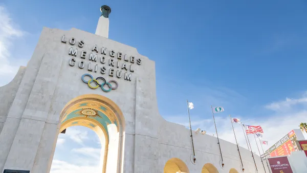 View looking up at stone entrance arch with name and Olympic rings at Los Angeles Memorial Coliseum.