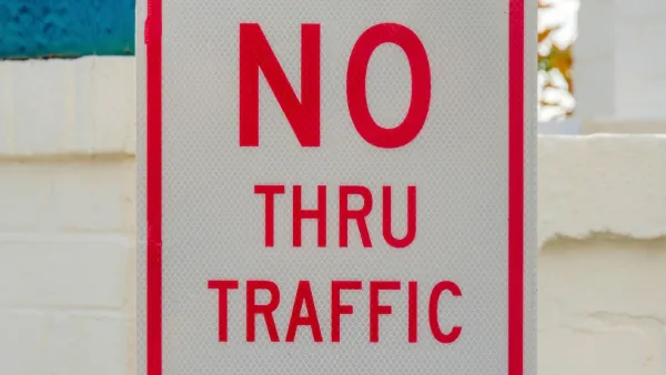 Close-up of white sign with red letters "NO THRU TRAFFIC"