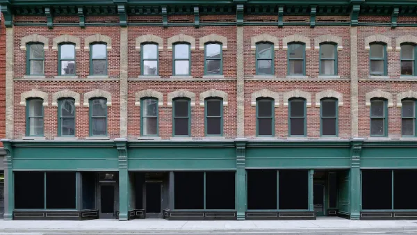 Brick building with storefronts on ground floor and apartments on two floors above.