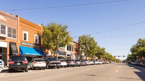View of small-town street with brick buildings and cars parked in diagonal parking with string lights going across street in Cleveland County, Oklahoma.