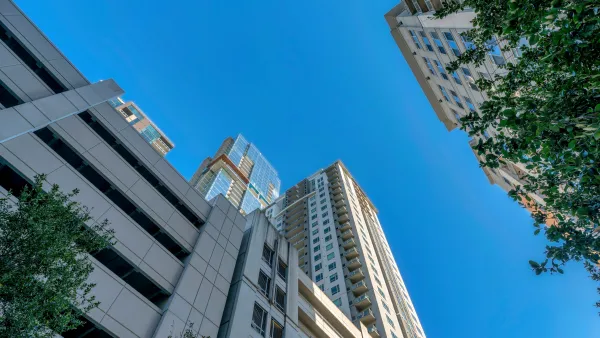 View from street level looking up at high-rise apartment building with multi0floor garage at bottom in Austin, Texas against blue sky
