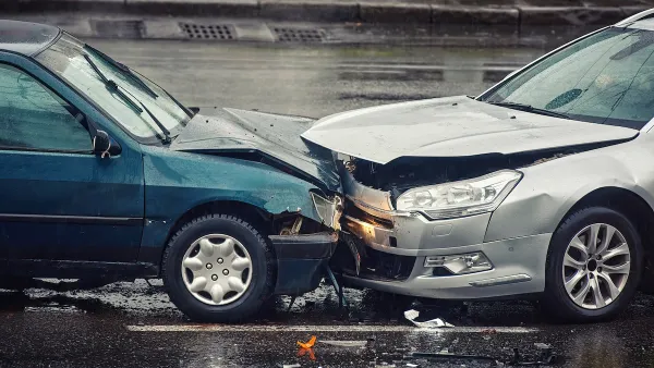 Two cars crashed head-on into each other on wet asphalt road.