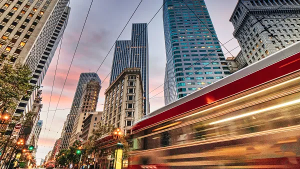 Blurred red San Francisco streetcar speeding past tall downtown buildings