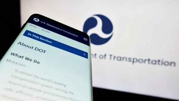Close-up of smartphone with USDOT website pulled up and screen with USDOT logo in background.