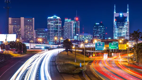 View of Nashville skyline at night with blurred highway lights in foreground.
