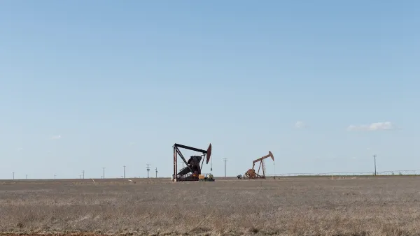 Two oil drilling derricks in vast field in West Texas.
