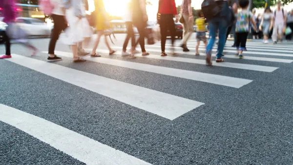 Close-up of blurred pedestrians crossing busy urban crosswalk.
