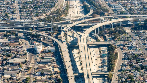 Aerial view of massive Los Angeles freeway interchange with dense housing and industrial areas around it.