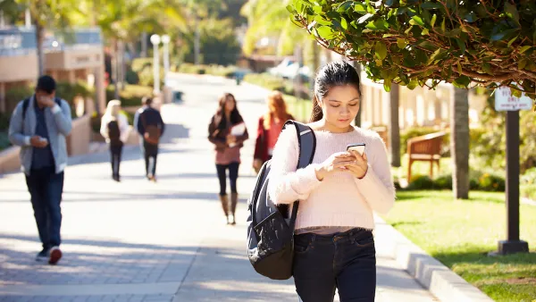 Students walking on sunny walkway on college campus.