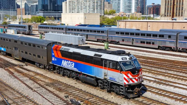 Blue, white, and red Metra commuter train with Chicago buildigns in background.