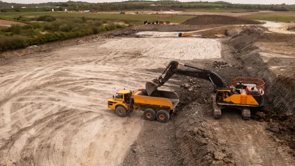 Aerial view of brownfield area with digger loading a dump truck.