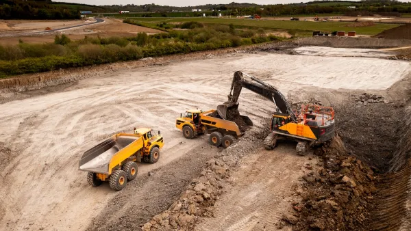 Aerial view of construction site with yellow dump truck and heavy machinery.