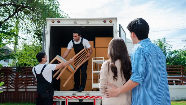 Couple watches as two movers loan furniture into back of box truck.