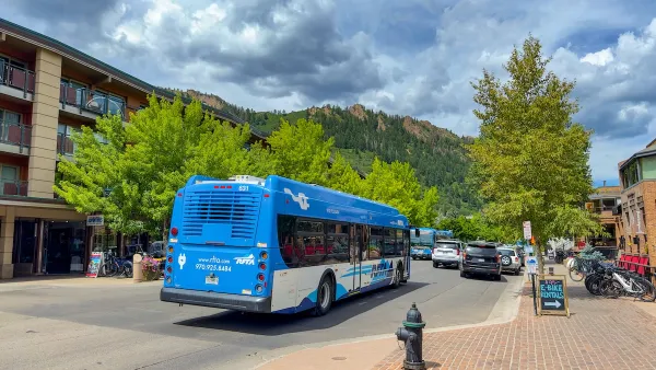 Blue public transit bus on street with mountains in background in Aspen, Colorado.