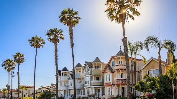 Historic Victorian homes in Huntington Beach, California with tall palm trees on a sunny day.