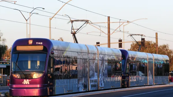 Purple Phoenix light rail train on rail at golden hour.