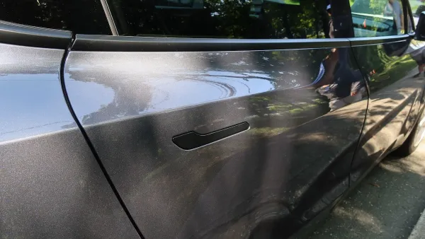 Close-up of door handle on outside of grey Tesla electric car.