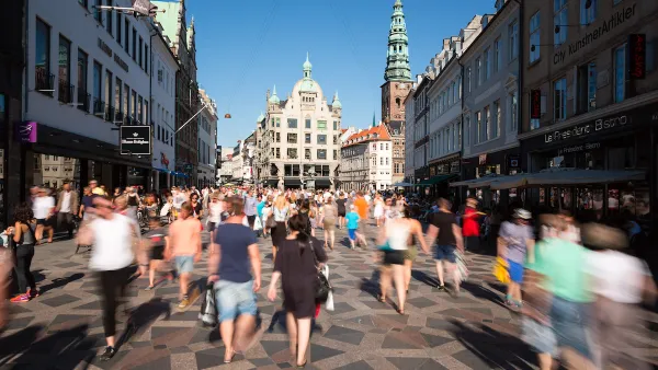 Blurred pedestrians on busy walkable street in Copenhagen, Denmark with old buildings in background
