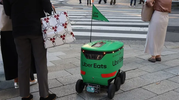 Green Uber Eats delivery robot waits at crosswalk in Tokyo, Japan.