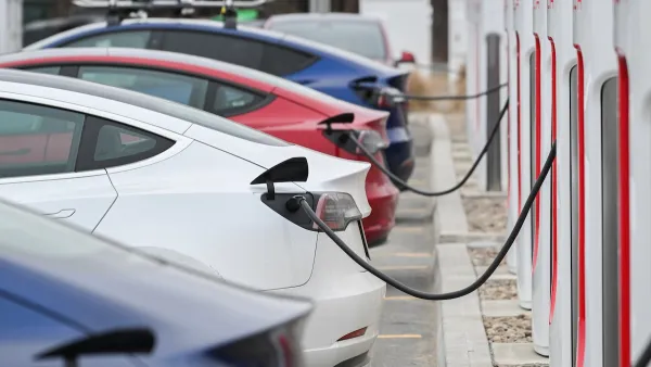 Close-up of four Tesla sedans parked and plugged in at charging station.