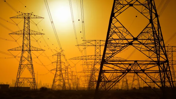 Large power towers sillhouetted against an orange sky
