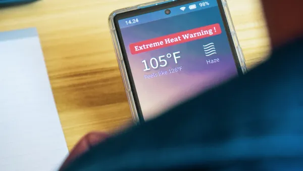 Close-up over shoulder of person holding smartphone with extreme heat warning and 105 degree temperature indicated.