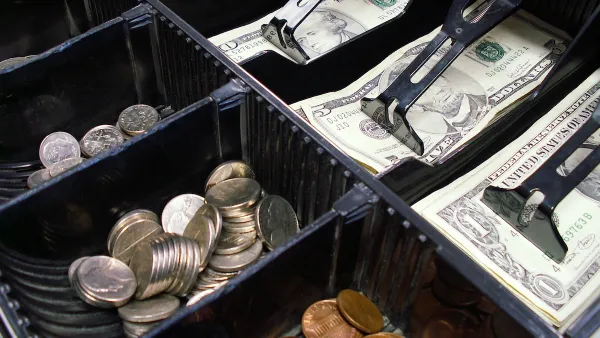 Close-up of cash drawer with various dollar bills and coins.