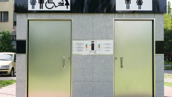 Outdoor public restrooms with two silver doors and icons for men, women, wheelchair accessibility, and baby changing above doors.