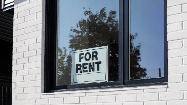 For Rent sign in window on white tiled wall.