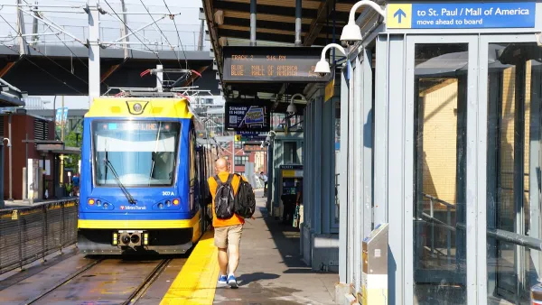 Outdoor train platform for light rail train in Minneapolis, Minnesota with passenger walking toward blue and yellow train.