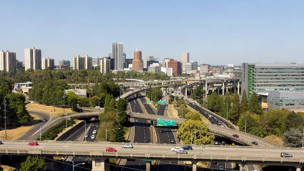 Aerial view of highway overpasses with Portland, Oregon skyline in background.