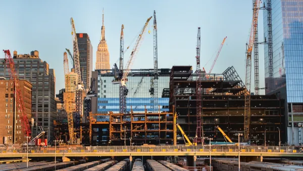 Construction site and cranes in New York City with Empire State Building visible in background.