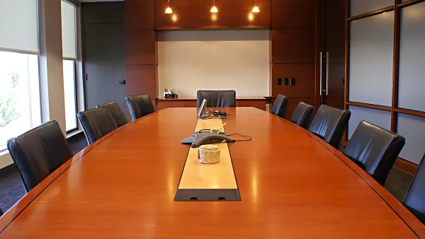 Large brown wood conference table surrounded by black leather chairs.