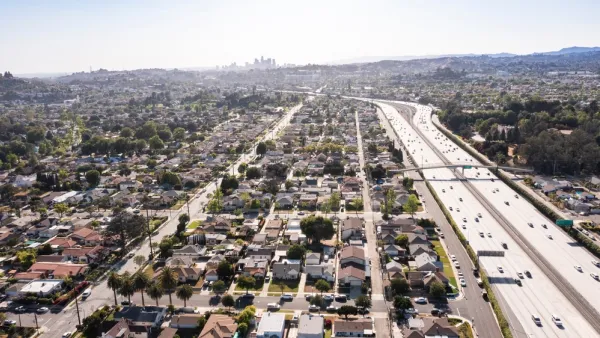 The Interstate 10 freeway cuts through residential neighborhoods in the city of Alhambra. Downtown Los Angeles is visible in the background,