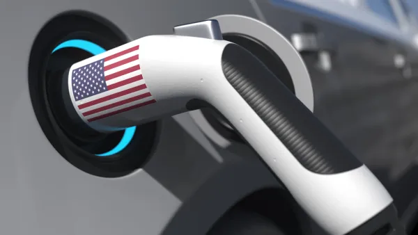 An electric vehicle charger with an American flag sticker is shown plugged into a car.