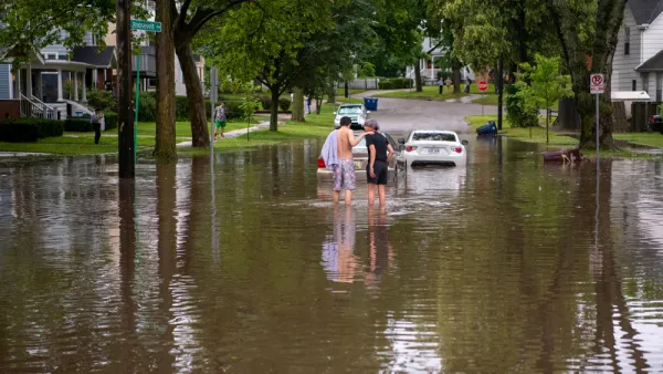 Two people walk down a residential street in ankle high water after a summer-time flood in Ann Arbor.