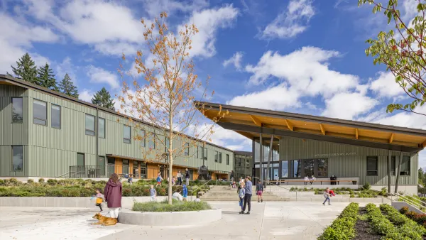 Green u-shaped school building with slanted roof and courtyard in the middle