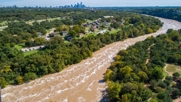 The Colorado River is flooded with brown water with the skyline of Austin, Texas in the background.