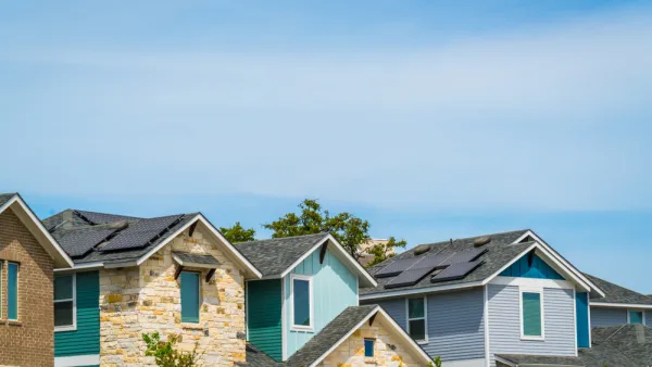 A row of homes, some brightly colored, on a sunny day in Austin, Texas.