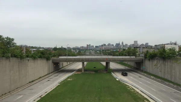 View from overpass of highway with one truck and green median with Baltimore city in the background
